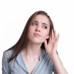 Woman looking like she hears a strange sound, making a hand to ear gesture