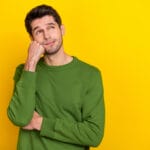 A 30ish man wearing a green sweater and wondering when he should replace his HVAC system