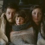 A family huddled under blankets during winter heat outage in Charlottesville, VA.