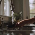 Photo of a Charlottesville-area home kitchen sink showing slow-draining water and a drain screen, illustrating early signs of grease buildup common in local households near downtown Charlottesville.
